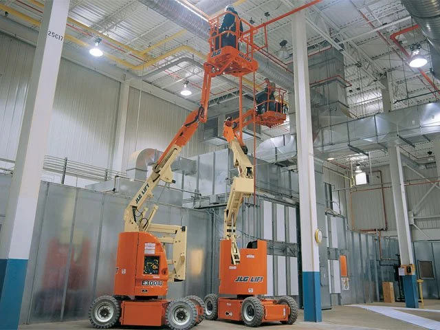 Dos plataformas elevadoras con personas trabajando en un interior industrial